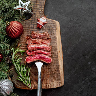 Pepperell's Fresh British Beef Ribeye Steak on a wooden platter with christmas baubles