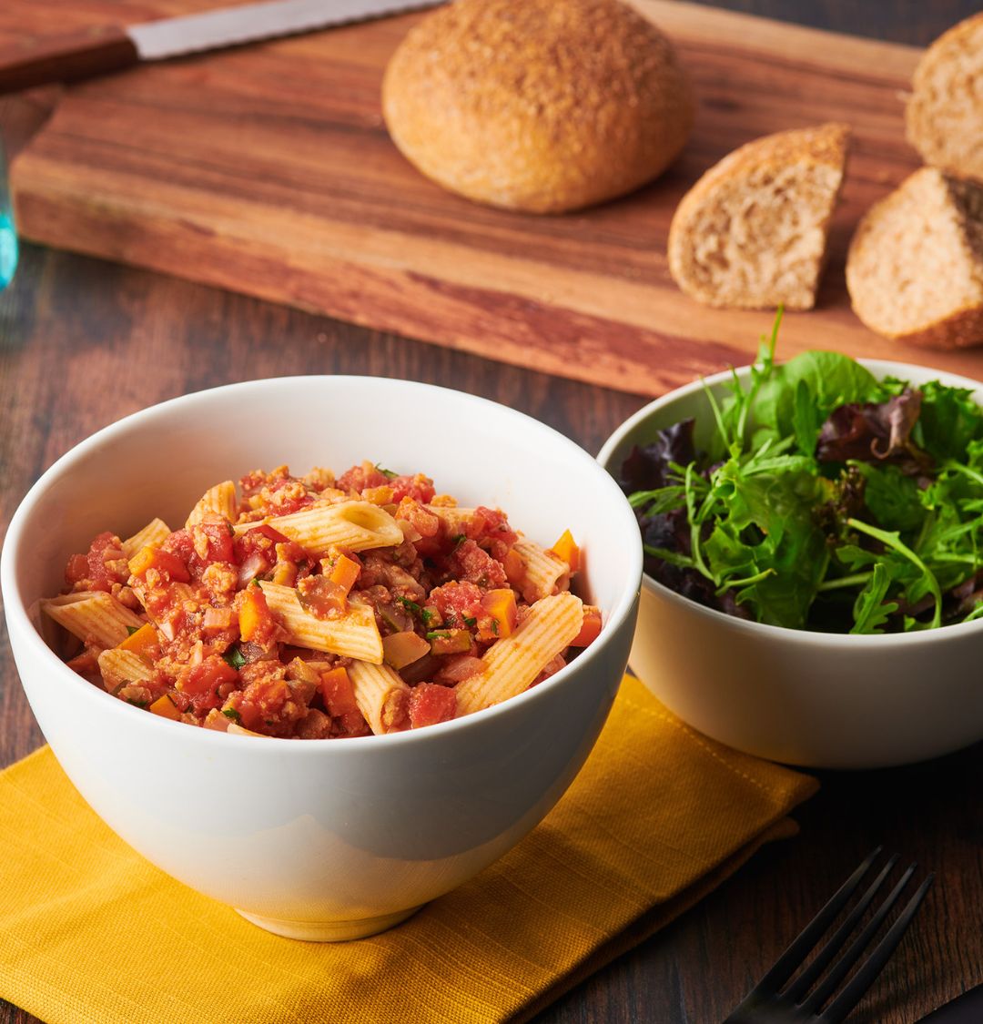 Novo Farina Pea Mince in a spaghetti bolognese with a bowl of salad and bread in the background